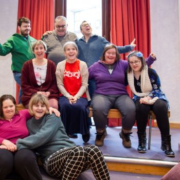 Run a mental health support group Group of people smiling and happy, sitting next to each other