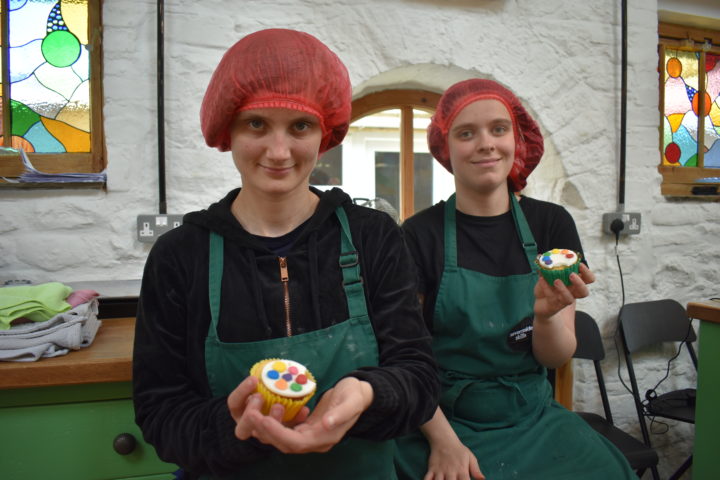 Two people we support holding cupcakes
