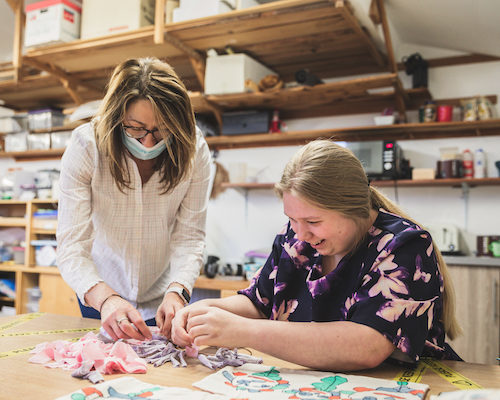 “The support workers are lovely and helpful. Chatting to them and to my friends has helped me gain more confidence.” Girl being supported by a support worker to make a rang wreath