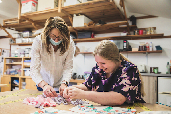 Girl being supported by a support worker to make a rang wreath