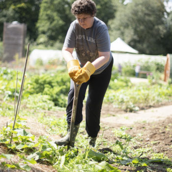 A person we support in the garden digging in soil with a spade