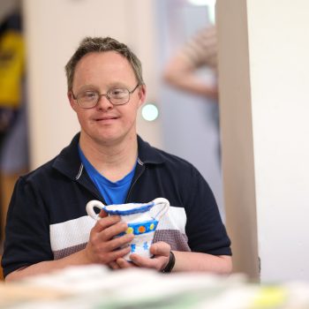 A person we support holding a piece of pottery