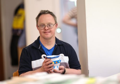 A man holding a piece of pottery he has made