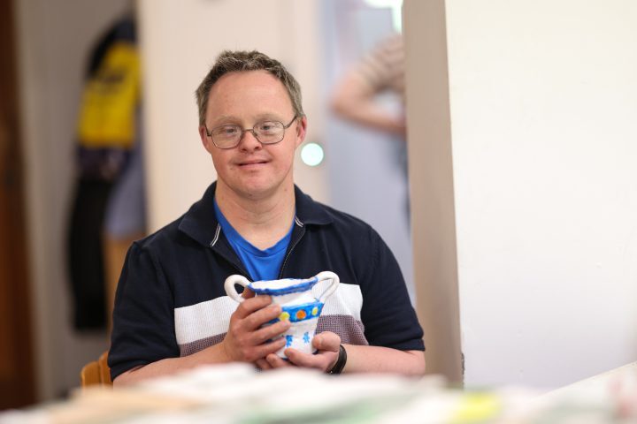 A person we support holding a piece of pottery