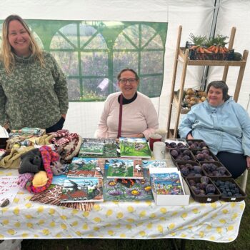 Three people sitting at a card stall