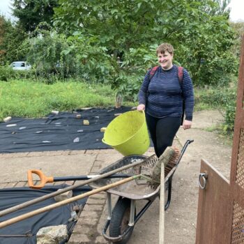 A person we support pushing a wheelbarrow