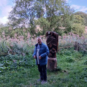 A person standing next to a totem pole