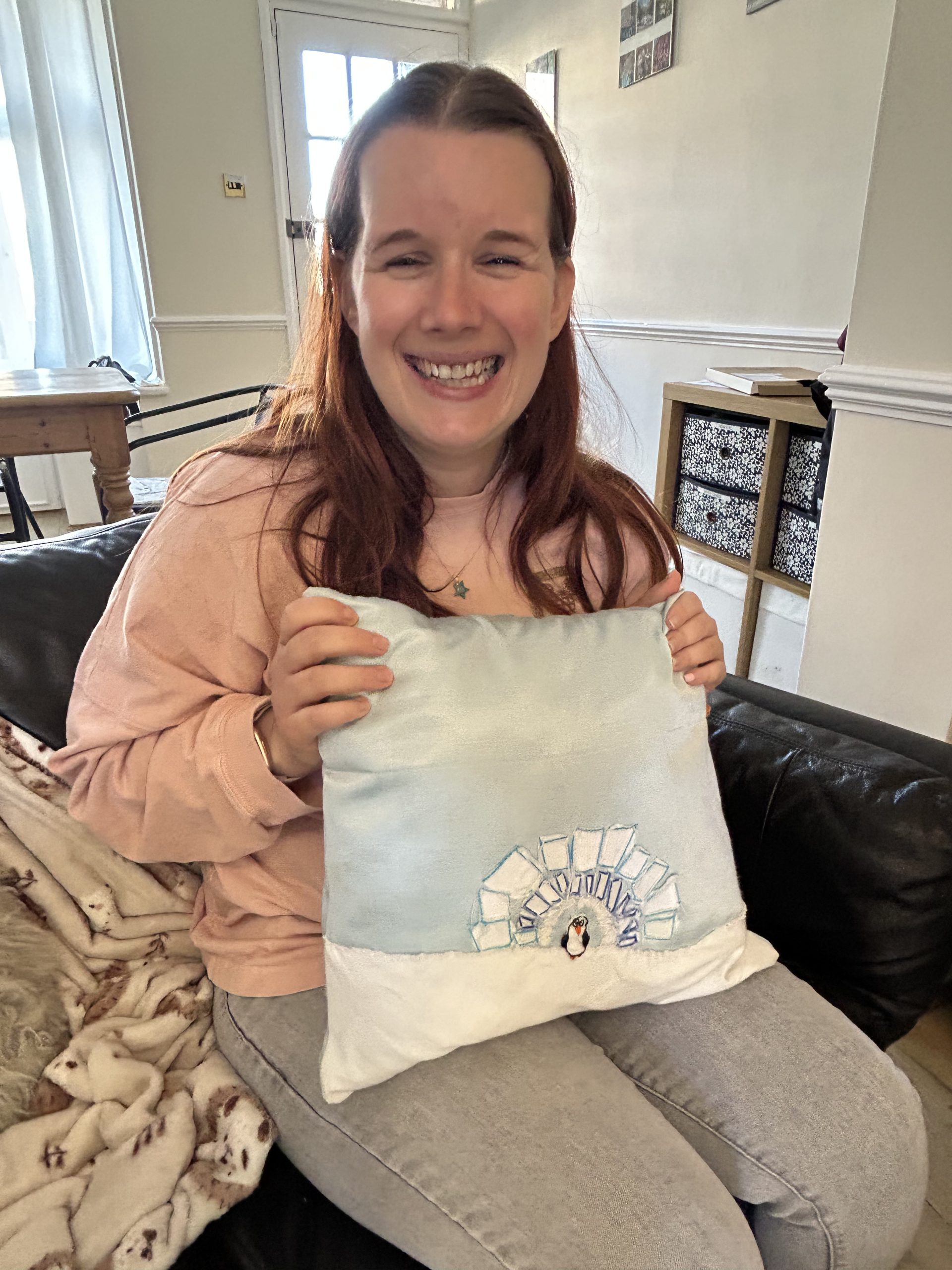 Nicki holding her cushion cover with a penguin