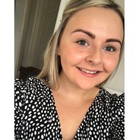 Dr Kate Sykes - headshot. She is wearing a black and white polkadot dress and smiling at the camera