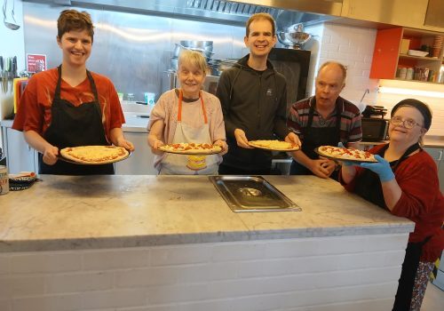 People holding food in a kitchen
