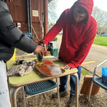 Someone using a drill to make a wooden sign