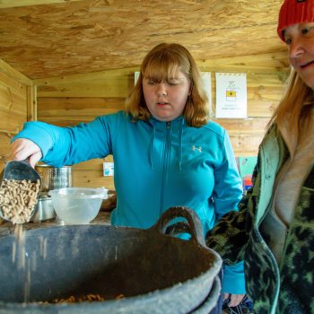 Amy and support worker doling out animal feed
