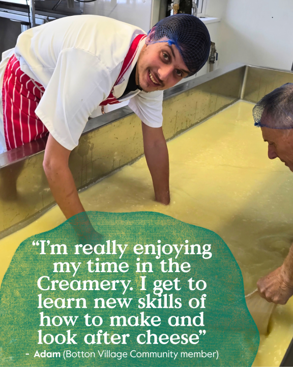 Community member learning cheesemaking skills in the Botton Village creamery, helping to make cheese in a large vat as part of Camphill Village Trust's award-winning dairy and creamery operation.