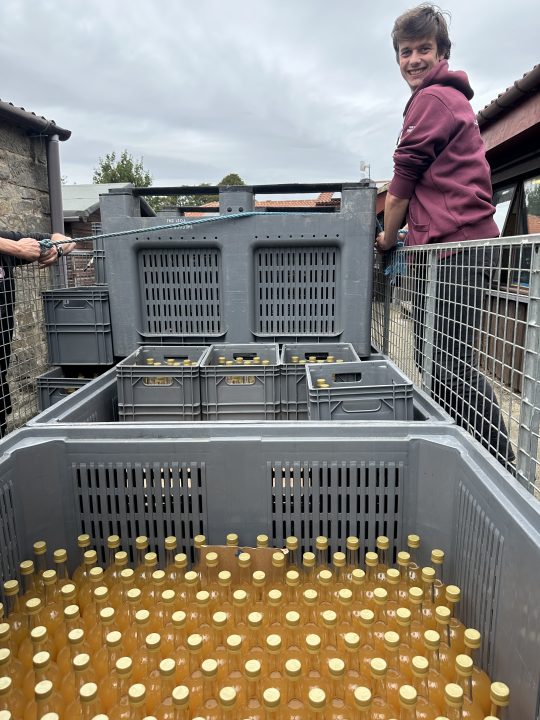 Adam helps transport crates of freshly bottled apple juice at Botton, with bottles made from apples harvested in the community's gardens.